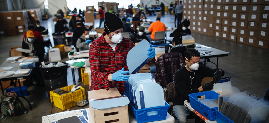 Workers wearing personal protective equipment builds splash guards during a mass manufacturing operation to supply New York City government with protection to distribute against COVID-19, Friday, March 27, 2020, at the Brooklyn Navy Yard in New York.