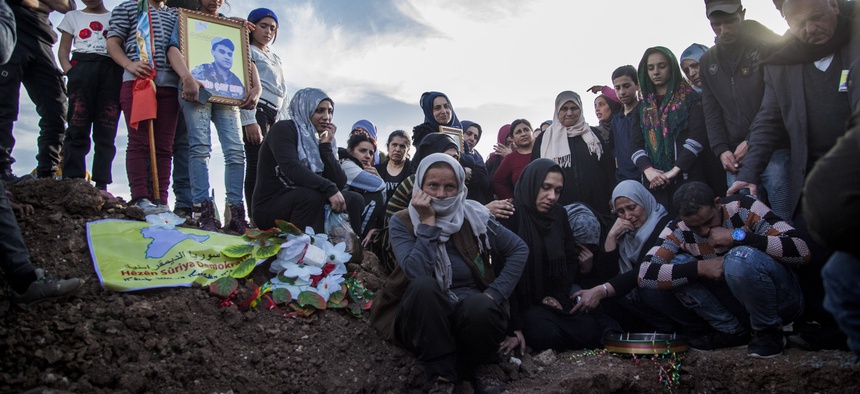 People attend a funeral of Syrian Democratic Forces fighter who was killed in a battle with remnants of of the Islamic State group in eastern Syria, in the town of Qamishli, Tuesday, Maarch 10, 2020.