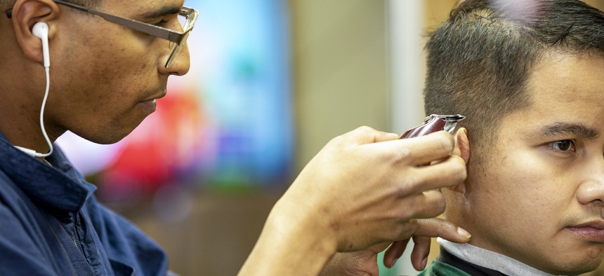 A Marine gives another service member a haircut in the barbershop aboard the USS Bataan in the Arabian Sea, March 2, 2020.