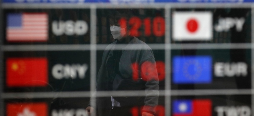 A man wearing a face mask is reflected on an electronic foreign currency exchange rates in downtown Seoul, South Korea, Tuesday, March 31, 2020.