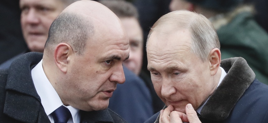 Russian President Vladimir Putin, right, speaks with Russian Prime Minister Mikhail Mishustin during a wreath-laying ceremony at the Tomb of the Unknown Soldier, near the Kremlin during the national celebrations of the 'Defender of the Fatherland Day'
