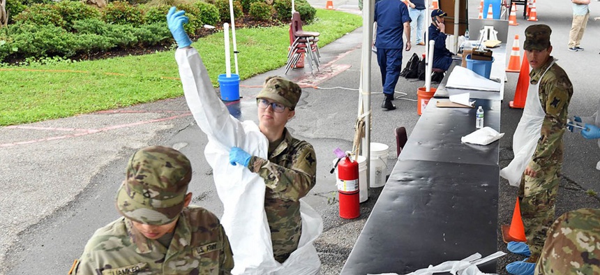 Soldiers with the Louisiana Army National Guard’s 256th Infantry Brigade Combat Team don protective suits as they prepare to administer nasal swabs to first responders and medical personnel at a mobile testing site in Westwego, Louisiana, March 21, 2020.
