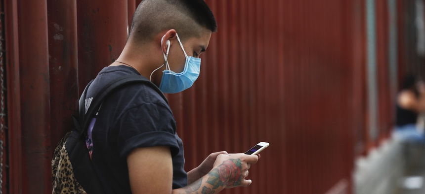 A man wearing a mask against the spread of the new coronavirus chats on his mobile phone outside a hospital in Iztapalapa in Mexico City, Thursday, April 30, 2020