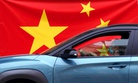 In this April 13, 2020, photo, a woman wearing a face mask drives her car by a Chinese flag placed on a street prior a curfew set up to help prevent the spread of the new coronavirus in Belgrade, Serbia.