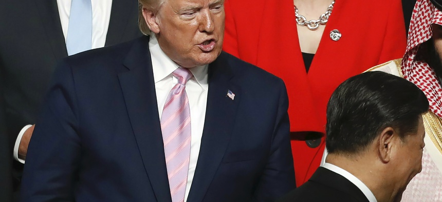 U.S. President Donald Trump, left, speaks to Chinese President Xi Jinping, bottom right, after they shook hands during family photo session at G-20 leaders summit in Osaka, Japan, Friday, June 28, 2019.