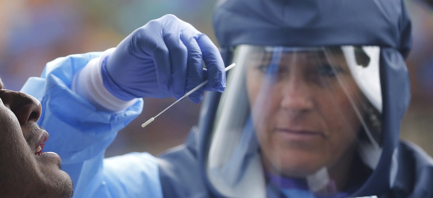 Salt Lake County Health Department public health nurse Lee Cherie Booth performs a coronavirus test outside the Salt Lake County Health Department, Wednesday, May 20, 2020, in Salt Lake City.