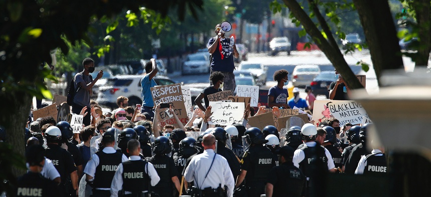 Protesters gather in front of a line of Uniformed U.S. Secret Service as demonstrators gather to protest the death of George Floyd, near the White House, Saturday, May 30, 2020, in Washington.