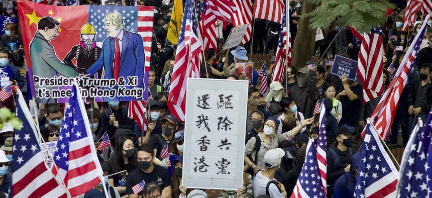 In this Dec. 1, 2019, file photo, protesters wave United States flags and a banner with the words "Chase away Communists and return my Hong Kong" during a rally march towards the U.S. consulate in Hong Kong.