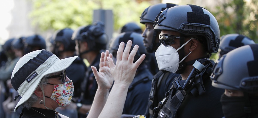 Rev. Susan Wilder of Kirkwood Presbyterian Church in Springfield, Va., prays at the police line, with a Bureau of Prisons Special Operations Response Team member, as demonstrators gather to protest the death of George Floyd, Wednesday, June 3, 2020.