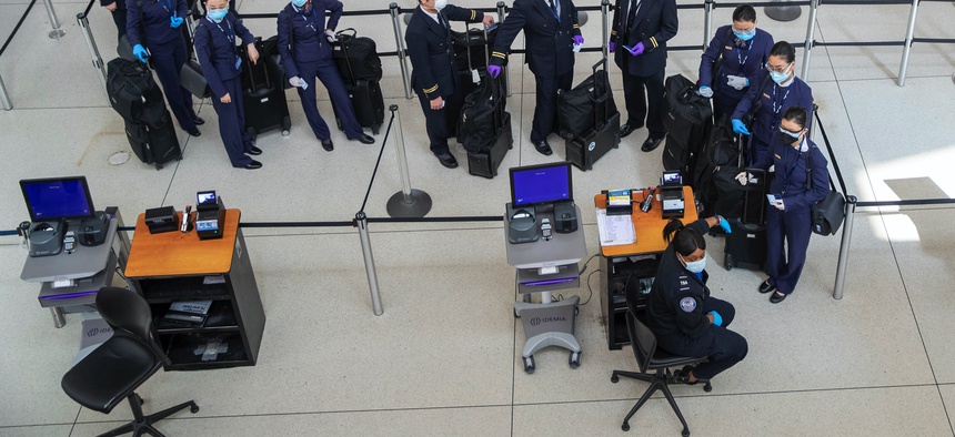 A flight crew wears masks to fend off coronavirus as they wait to go through a TSA security checkpoint, Tuesday, March 24, 2020, at JFK airport in New York.
