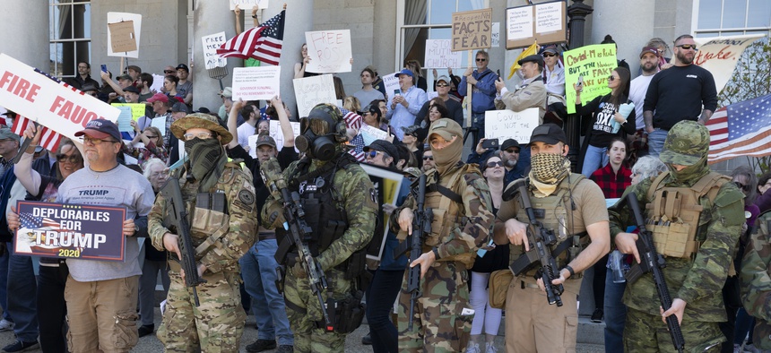 In this May 2, 2020, file photo, people, including those with the boogaloo movement, demonstrate against business closures due to concern about COVID-19, at the State House in Concord, N.H.