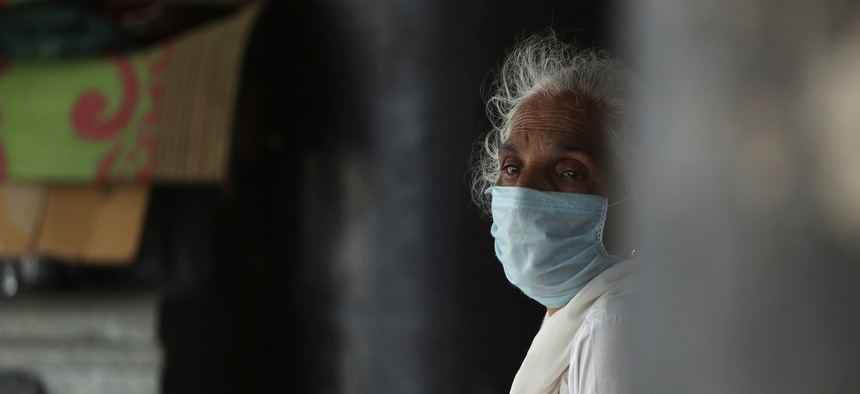 A woman wearing a face mask as a precaution against the coronavirus sits at a bus station in Jammu, India, Thursday, July 9, 2020. India has overtaken Russia to become the third worst-affected nation by the coronavirus pandemic.