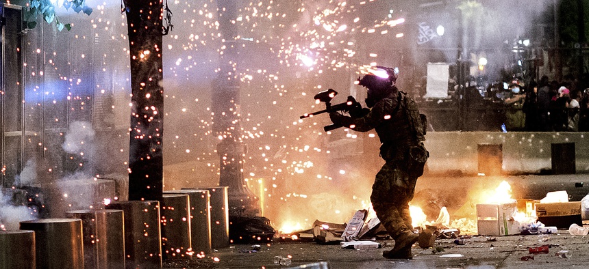 A federal officer fires crowd control munitions at Black Lives Matter protesters at the Mark O. Hatfield United States Courthouse on Friday, July 24, 2020, in Portland, Ore.