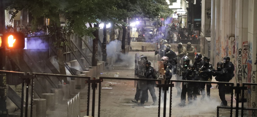 Federal officers walk out in formation to launch tear gas at demonstrators during a Black Lives Matter protest at the Mark O. Hatfield United States Courthouse Sunday, July 26, 2020, in Portland, Ore.