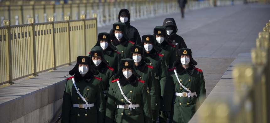 Paramilitary policemen wear face masks as they march in formation into a pedestrian underpass next to Tiananmen Square in Beijing, Tuesday, Feb. 4, 2020.