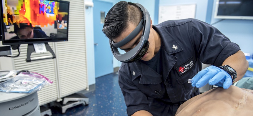 A sailor wears augmented goggles to relay a live-stream video of the procedure to a doctor in San Diego during a tele-procedural mentorship scenario to test the capabilities of the augmented goggle technology.