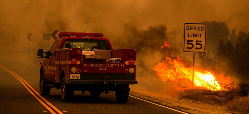 A Los Angeles County Fire Department truck drives through smoke, next to a small area burning in the Bobcat Fire in Juniper Hills, Calif., Friday, Sept. 18, 2020.