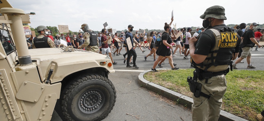 DC National Guard soldiers and other law enforcement personnel watch as demonstrators protest Saturday, June 6, 2020, along Independence Avenue in Washington, over the death of George Floyd, a black man who was in police custody in Minneapolis.