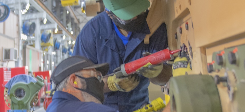 Chris Chatman, standing, and Michael Stevens prepare a U.S. Marine Corps variant M1 Abrams hull for the assembly of suspension components in Anniston Army Depot’s Combat Vehicle Repair Facility.