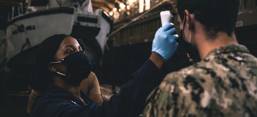 A Marine assigned to amphibious dock landing ship USS Comstock conducts COVID-19 mitigation procedures on sailors aboard Patrol Boats Mk VI assigned to Commander, Task Force 75 in the Philippine Sea, Oct. 6, 2020.