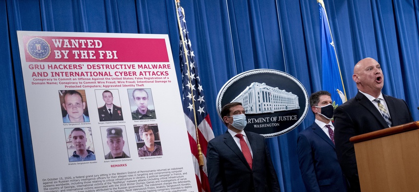 A poster showing six wanted Russian military intelligence officers is displayed at a news conference at the Department of Justice on Oct. 19, 2020, in Washington.