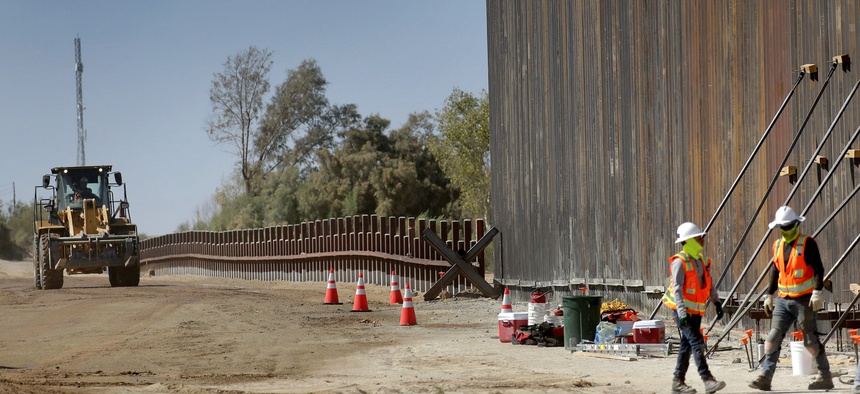In this Sept. 10, 2019, file photo, government contractors erect a section of Pentagon-funded border wall along the Colorado River, in Yuma, Ariz.