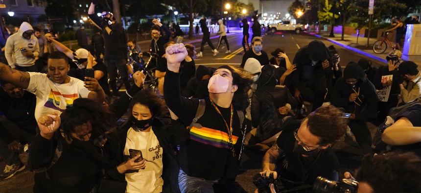 A helicopter circles low as demonstrators kneel to protest the death of George Floyd, Monday, June 1, 2020, near the White House in Washington. Floyd died after being restrained by Minneapolis police officers.