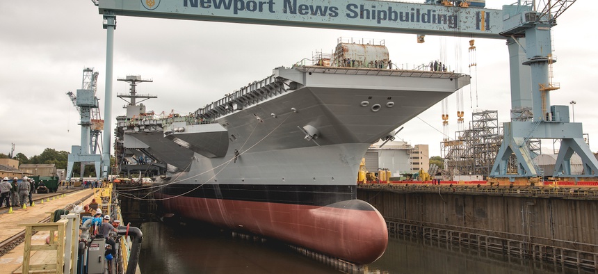 Workers flood the dry dock holding the aircraft carrier John F. Kennedy.