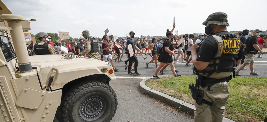 DC National Guard soldiers and other law enforcement personnel watch as demonstrators protest Saturday, June 6, 2020, along Independence Avenue in Washington, over the death of George Floyd, a black man who was in police custody in Minneapolis.
