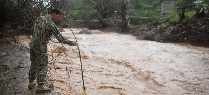 U.S. Army 1st Special Force Command Staff Sgt. Eric Reyes checks the depth of a river that was caused when heavy rains fell on the area days after Hurricane Maria swept through the island on October 7, 2017 in Barranquitas, Puerto Rico. 