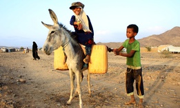 A girl rides a donkey carrying jerry cans filled with water from a cistern at a make-shift camp for displaced Yemenis in severe shortage of water, in the northern Hajjah province on March 24, 2020.