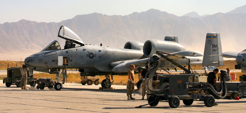 An A-10 Thunderbolt II takes off on a combat mission in Afghanistan as A-10 crew chiefs, weapons loaders, and an avionics specialist ready others for another mission.