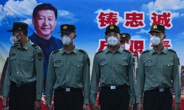 Soldiers of the People's Liberation Army's Honour Guard Battalion wear protective masks as they stand at attention in front of photo of China's president Xi Jinping at their barracks outside the Forbidden City, near Tiananmen Square