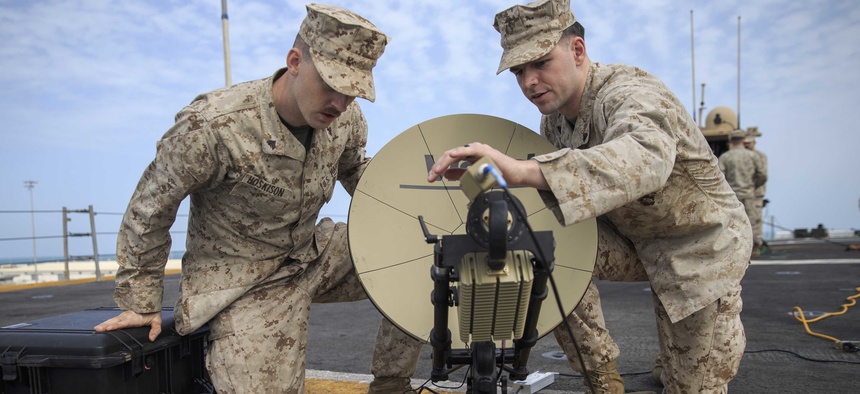 U.S. Marine Corporals Josrdan Hoskison, left, and Jacob Jusczak, right, both data system administrators with the 22nd Marine Expeditionary Unit, set up a Multi-Mission Terminal satellite on the flight deck of the USS Kearsarge.