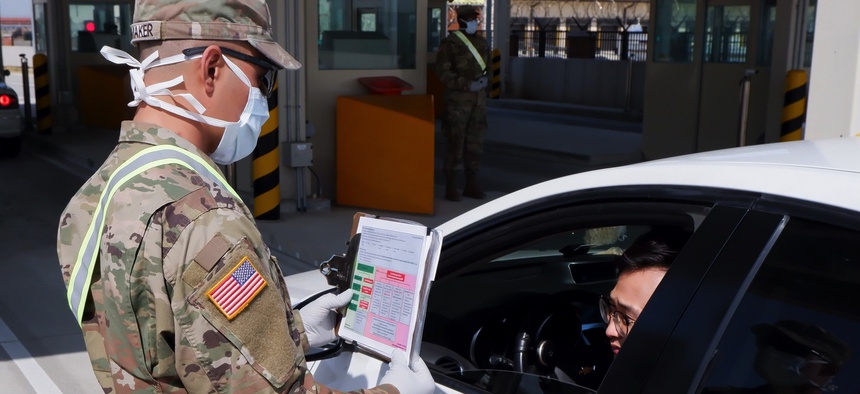 A soldier from the 2nd Armored Brigade Combat Team interviews a driver coming through the Adams Gate at U.S. Army Garrison-Humphreys, South Korea.