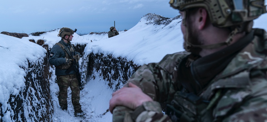 Ukrainian servicemen walk along a snow-covered trench guarding their position at the frontline near Vodiane, about 750 kilometers (468 miles) south-east of Kyiv, eastern Ukraine, Saturday, March 5, 2021.